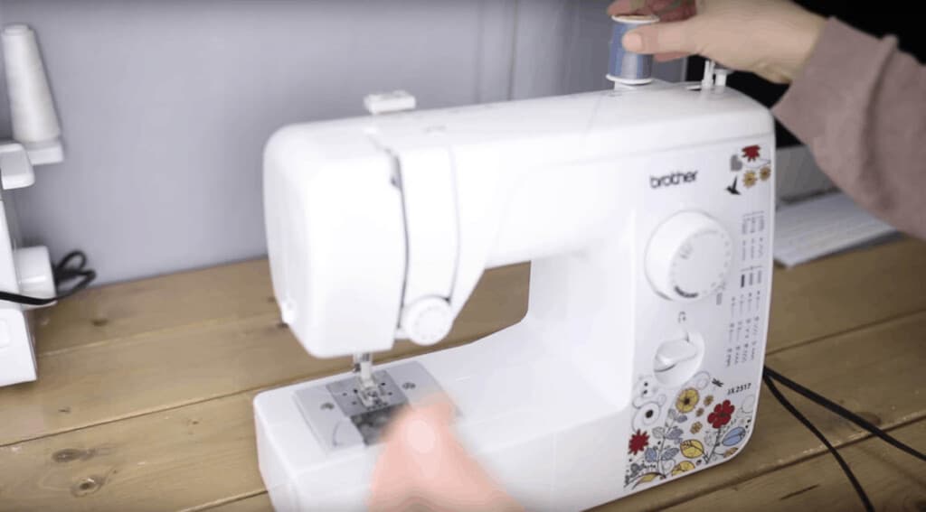 hand holding the thread on top of a sewing machine