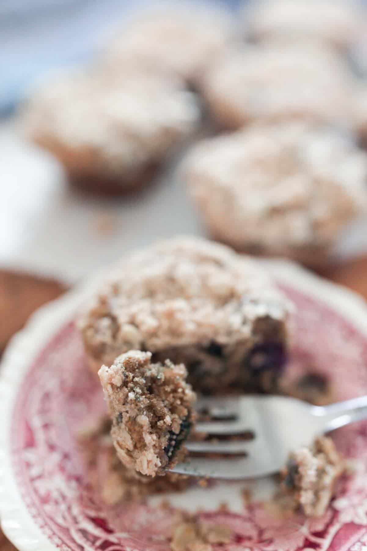 close up of a half of sourdough blueberry muffin on a countertop with more muffins on a wire rack in the background