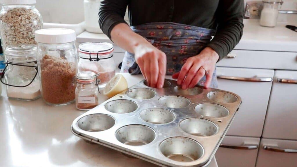 women greasing a muffin tin with her hands