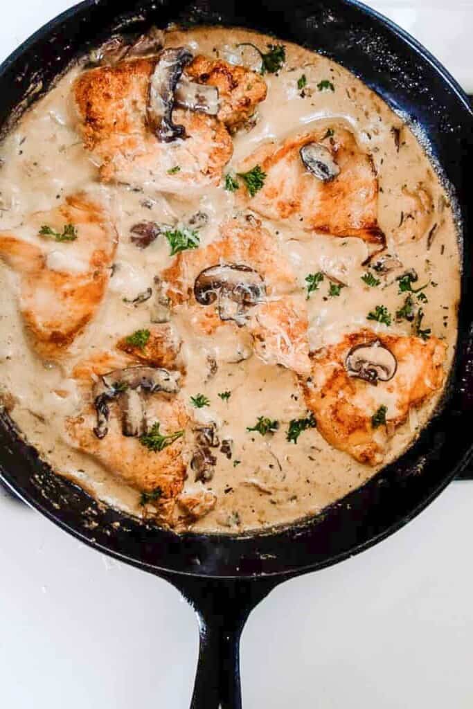 cast iron skillet with creamy mushroom chicken sauce with herbs