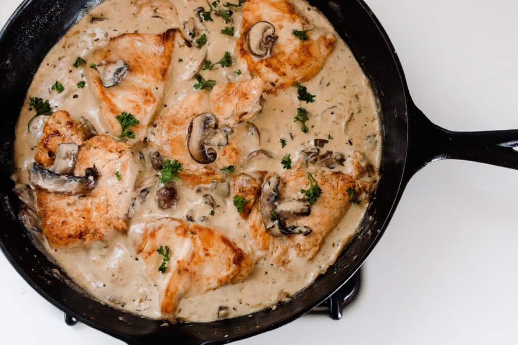 creamy chicken mushrooms sauce in a cast iron skillet topped with herbs