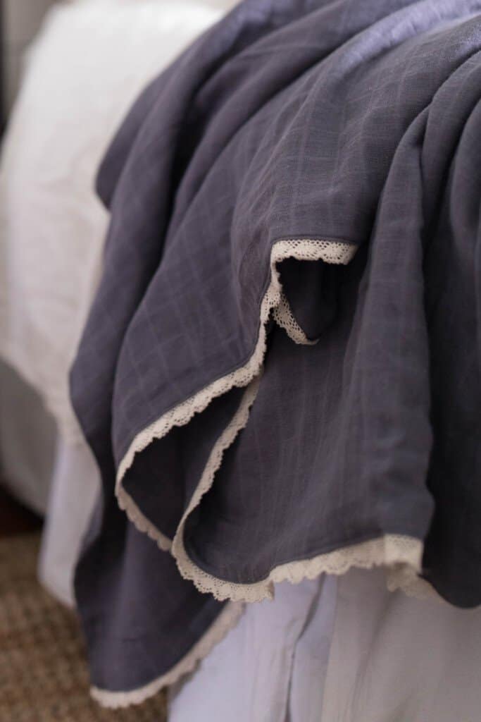 diy gauze swaddle blankets with lace placed on a bed with a white comforter