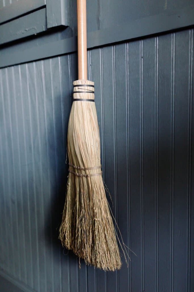 handmade wooden broom against a blue green