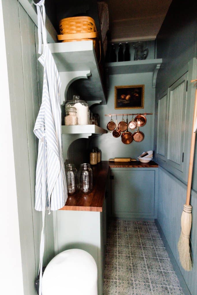 farmhouse pantry reveal with custom cabinetry with dark wood stained countertops, shelving, patterned tile, and copper pots hanging on the wall.