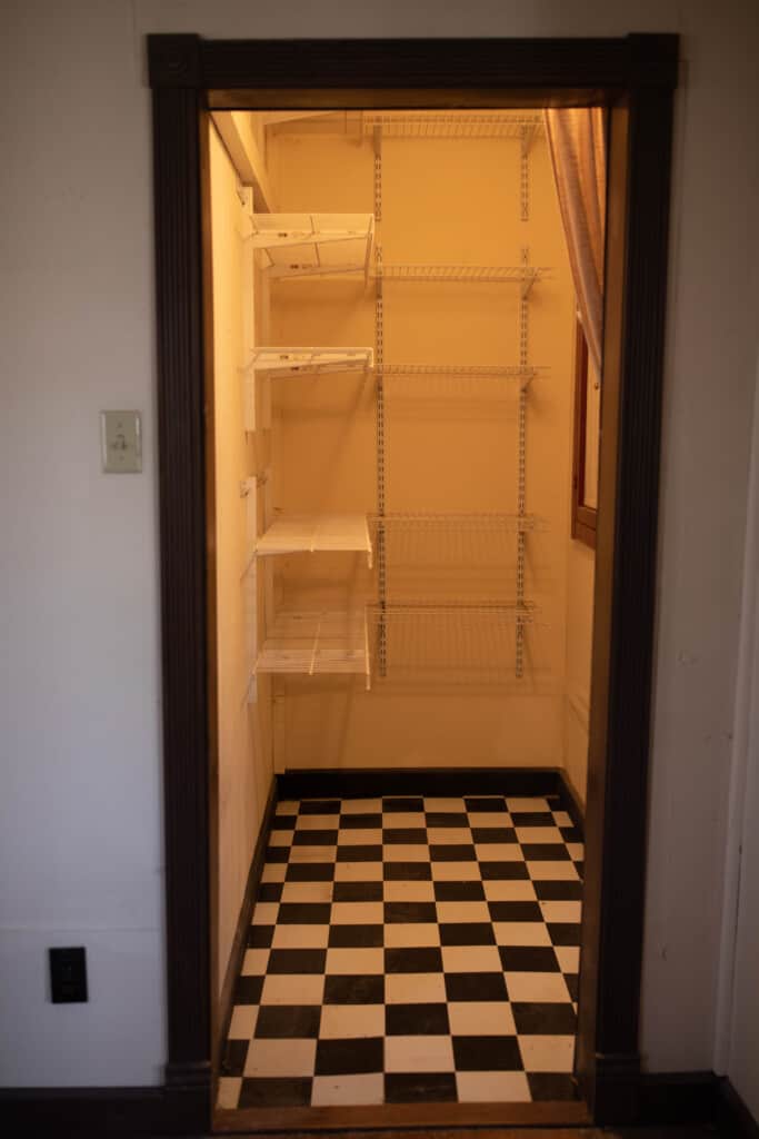 Pantry before with black and white tile and wire shelving