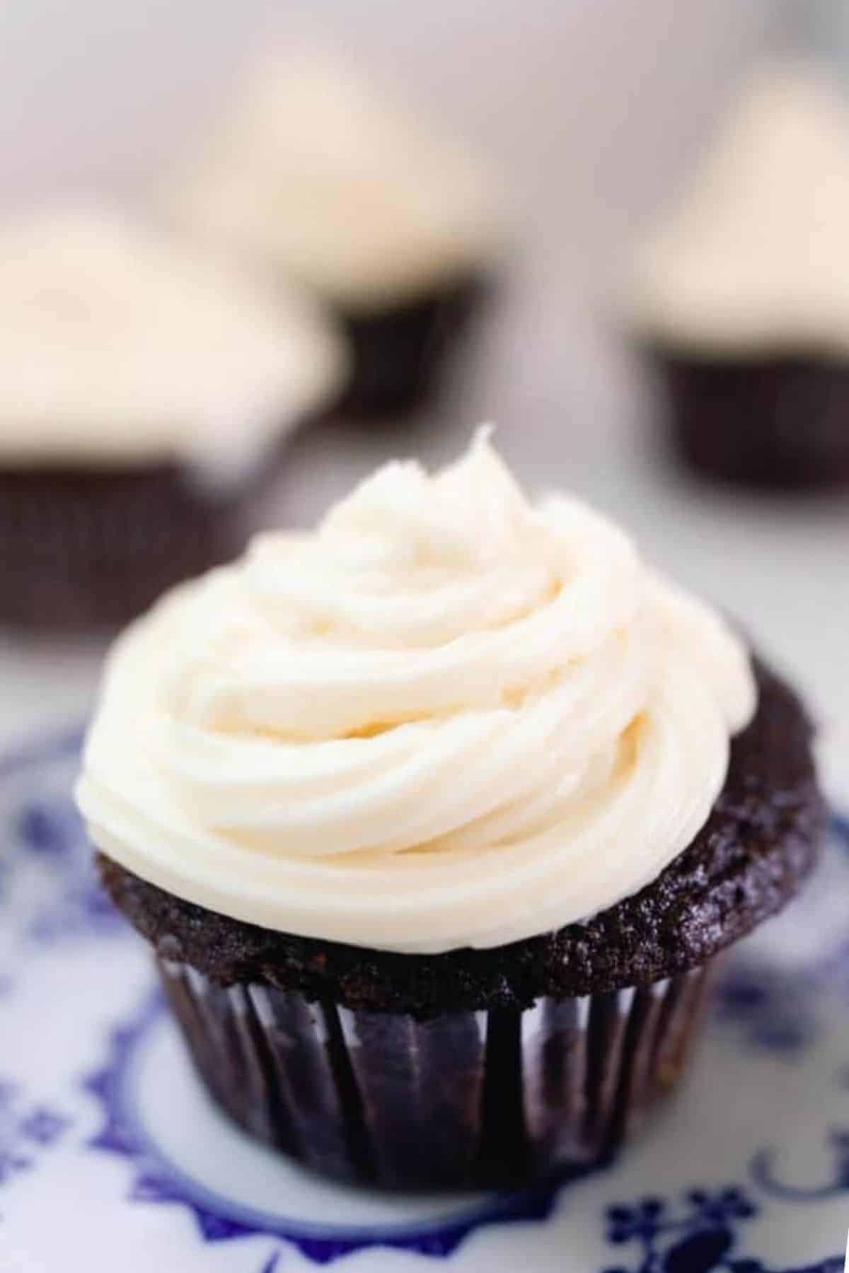 sourdough cupcake with cream cheese buttercream frosting on a white and blue antique plate