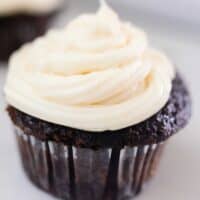 close up picture of a sourdough cupcake with white frosting on an white antique stove