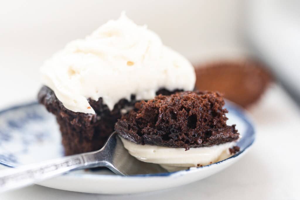 sourdough cupcake with cream cheese buttercream frosting on a blue and white antique plate with a spoon