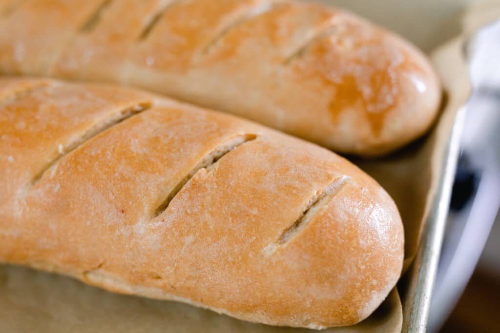 close up picture of two sourdough French breads on a parchment lined baking sheet