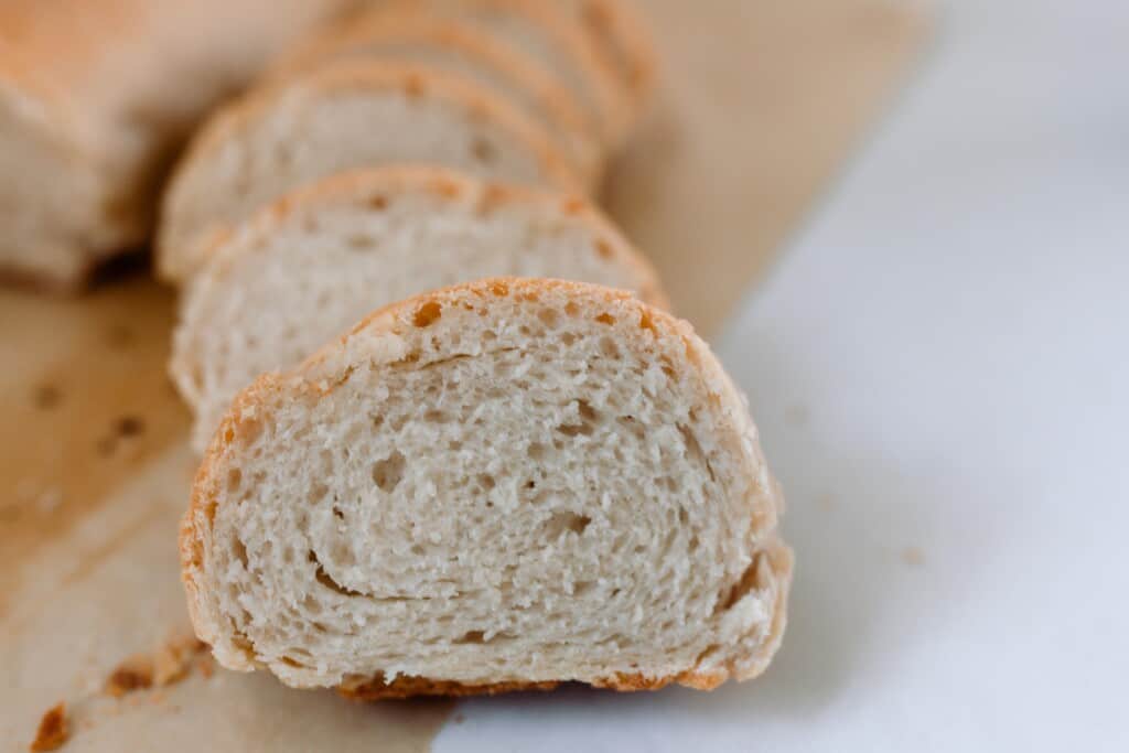 slices of French sourdough bread on parchment paper on a white quarts countertop