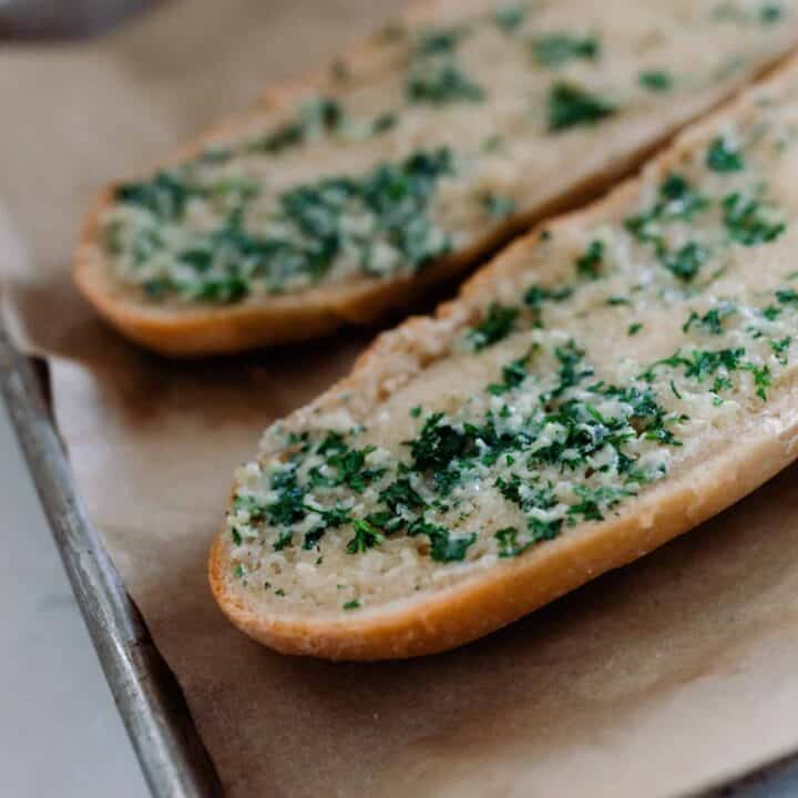 sourdough French bread cut in half and covered with garlic butter baked in the oven on parchment lined baking sheets