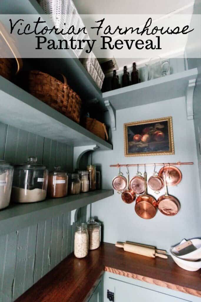 victorian farmhouse pantry with blue green walls, cabinets with wood countertops, shelving, and copper pots handing on the wall