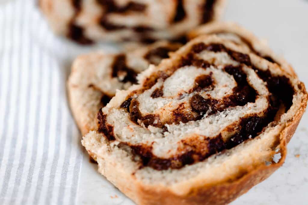 slices of swirled cinnamon raisin sourdough bread on a white and gray stripped tpwe;