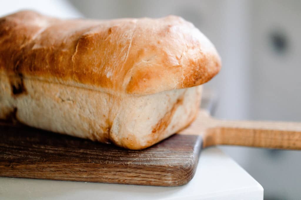 loaf of sourdough cinnamon raisin bread on a wood cutting board