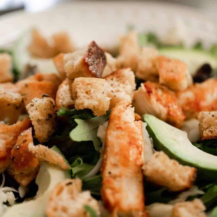 sourdough croutons on top a leafy salad with avocado