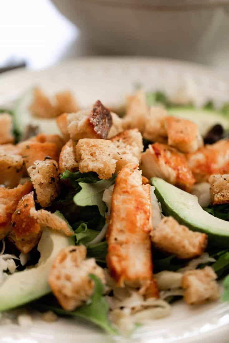 sourdough croutons on top a leafy salad with avocado