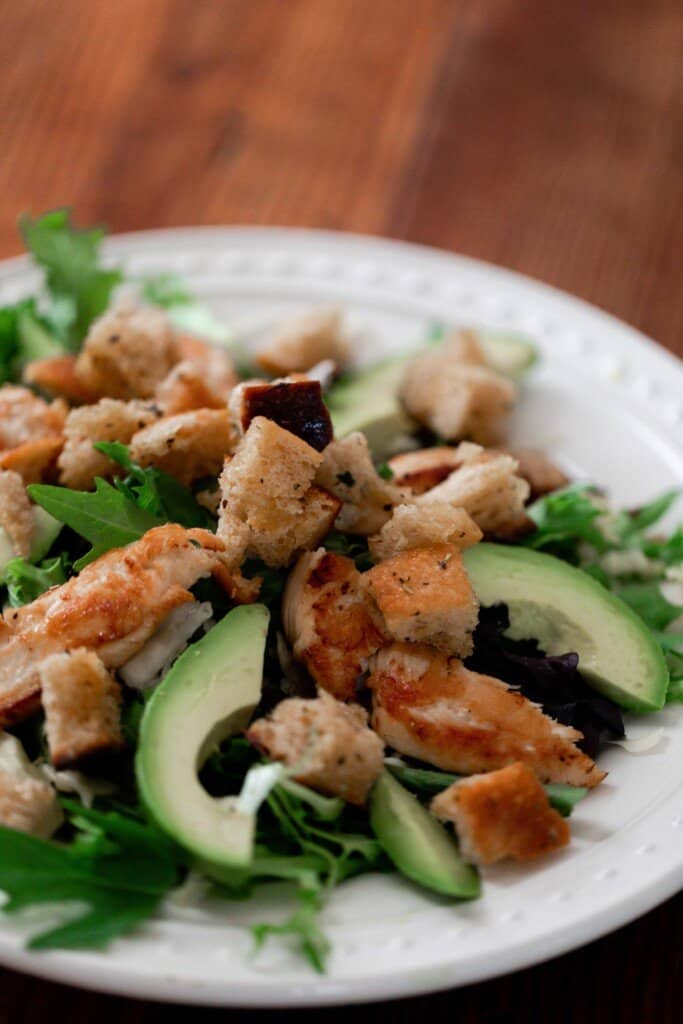 grilled chicken salad with croutons and sliced avocado