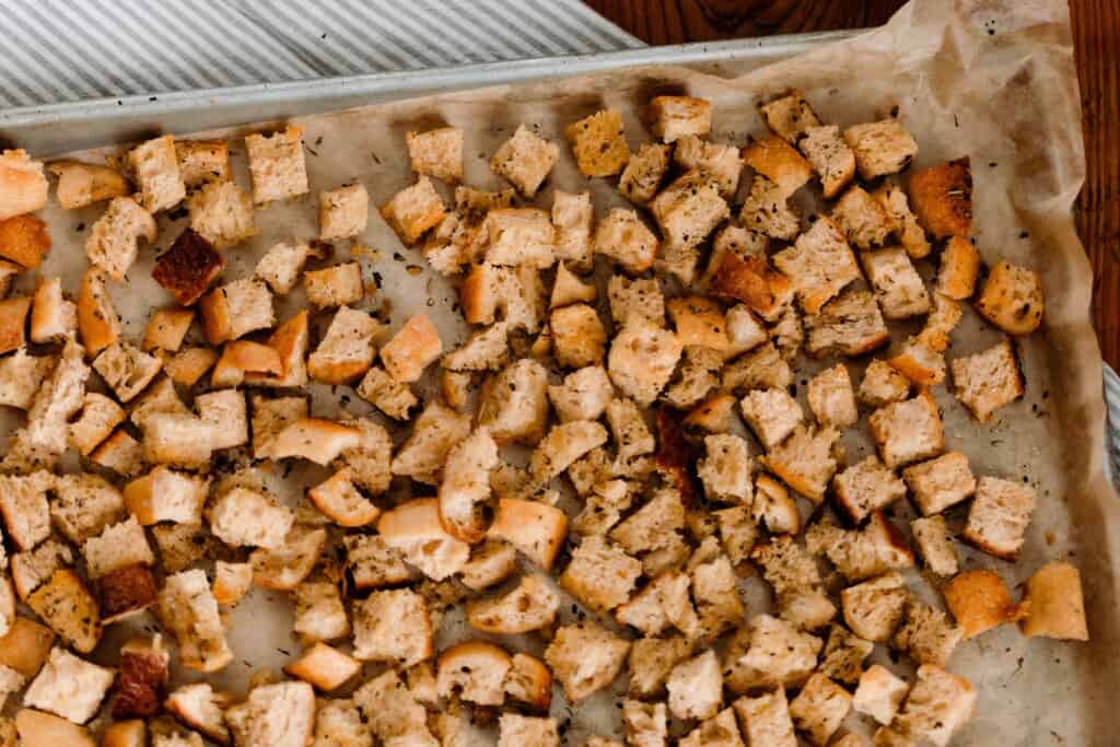 golden and crunchy sourdough croutons on a parchment lined baking sheet