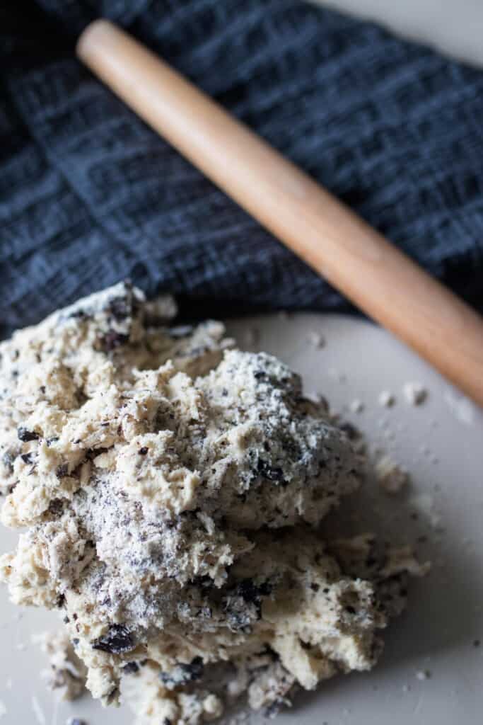 sourdough scone dough on a white countertop with a rolling pin on a blue towel in the background