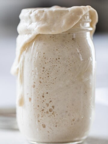 bubbly overflowing sourdough starter a white countertop