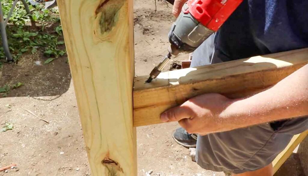 ma drilling in a 2x4 into a post to create a hand rail.