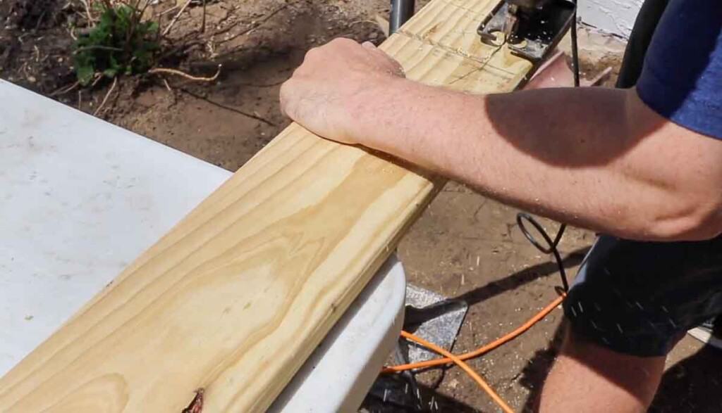 man cutting out a space for hand rail post on a stair tread.