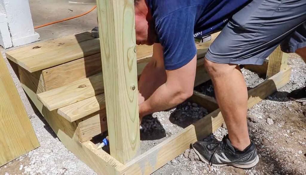 man adding wood glue to the top of stair stringers with a post