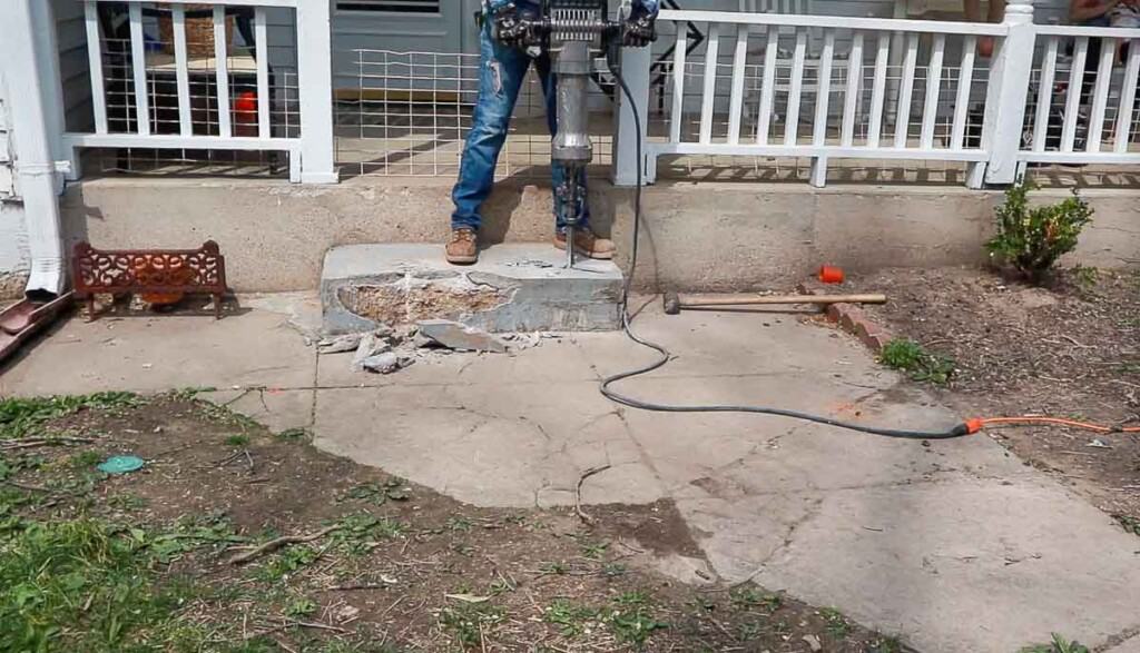 man jack hammering a concrete step off a front porch