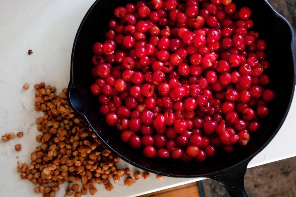 pitted cherries in a cast iron skillet ton a white quartz countertop