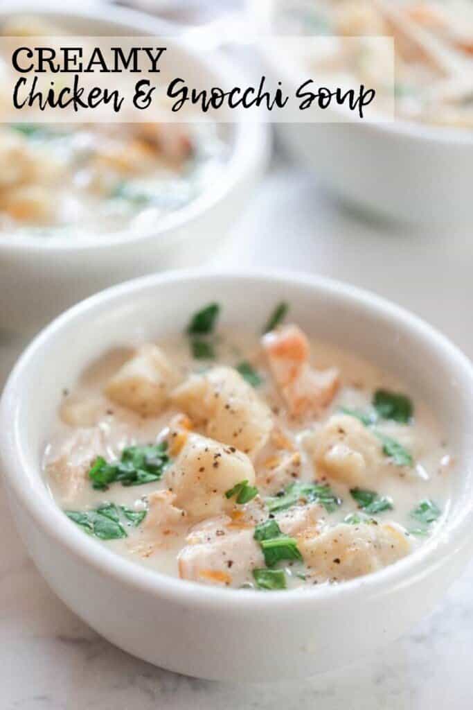 three white bowls filled with homemade gnocchi soup topped with fresh herbs on a white and gray quarts countertop