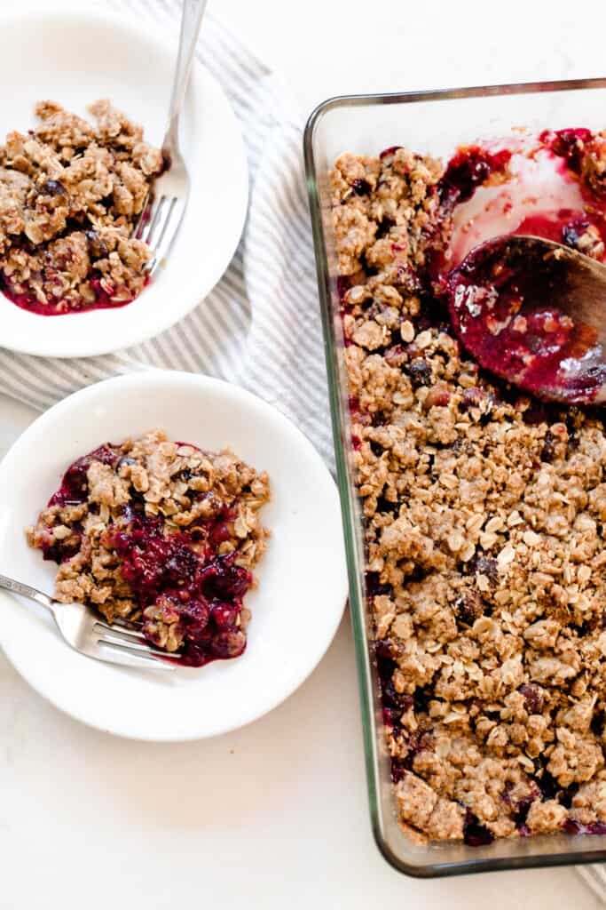 a baking dish of einkorn berry crisp with two bowl os crisp to the left