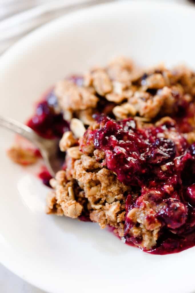 close up picture of a berry crisp made with einkorn flour in a white bowl