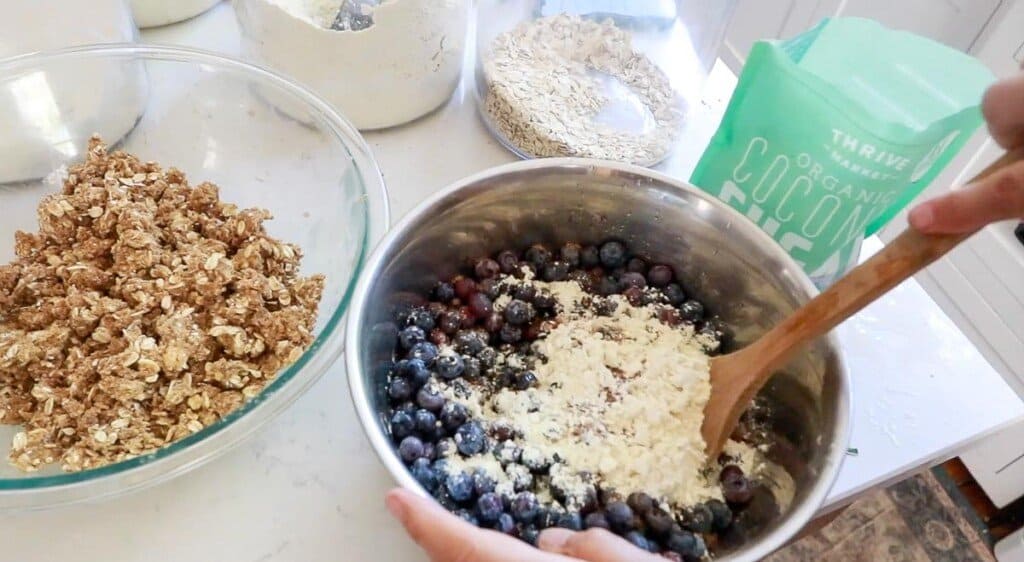 flour and coconut sugar on blueberries in a metal bowl