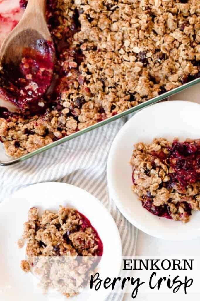overhead photo of two white bowls filled with einkorn berry crisp with a baking dish of crisp behind the bowls in a background
