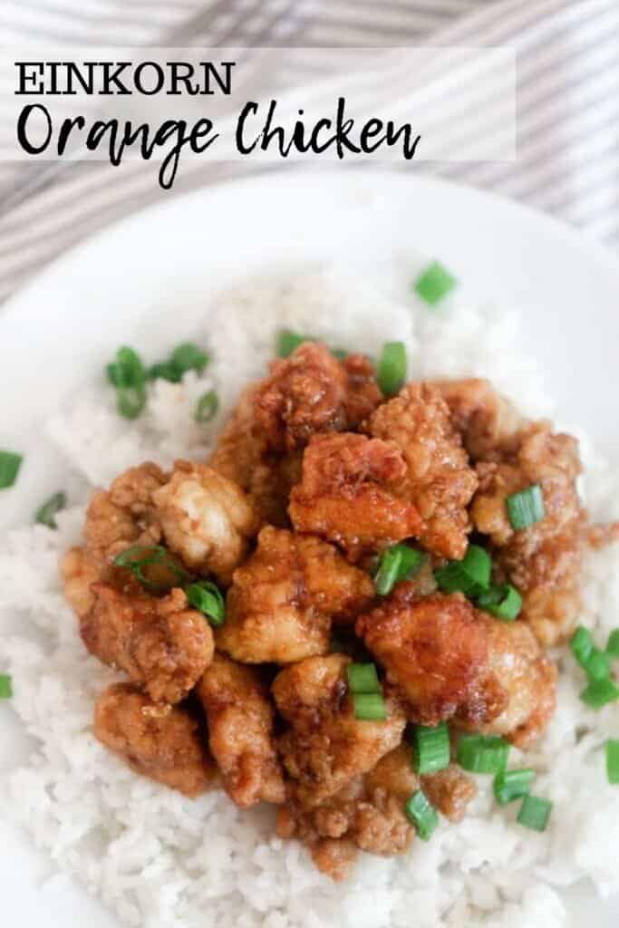 overhead photo of homemade orange chicken on top of white rice and topped with green onions on a white plate with a gray and white napkin in the background