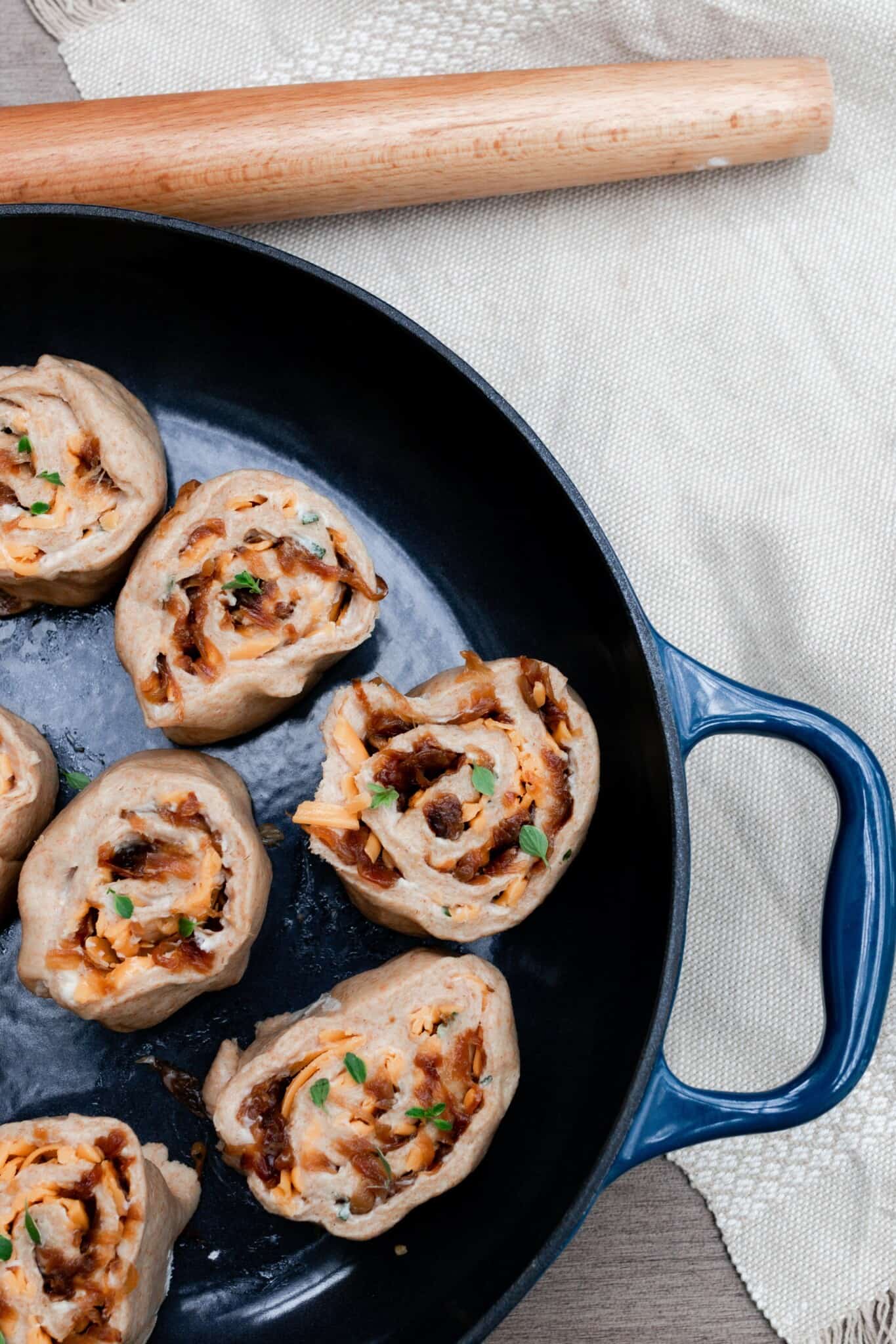 sourdough herb and cheese rolls unbaked in a cast iron skillet