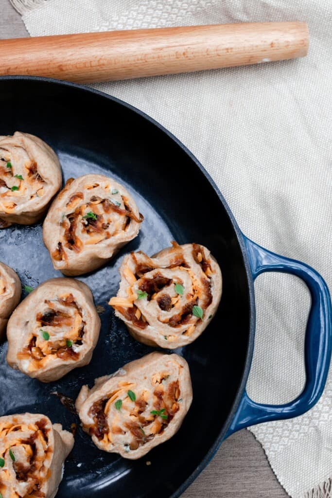 sourdough herb and cheese rolls unbaked in a cast iron skillet