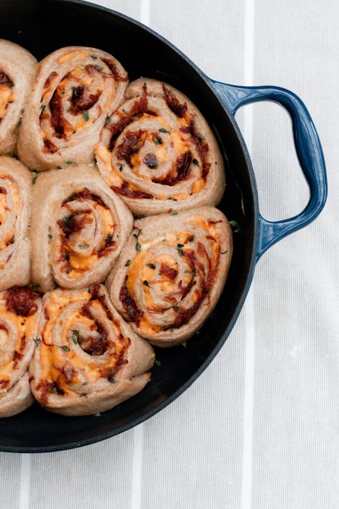 overhead photo of a cast iron skillet full of sourdough cheese rolls.