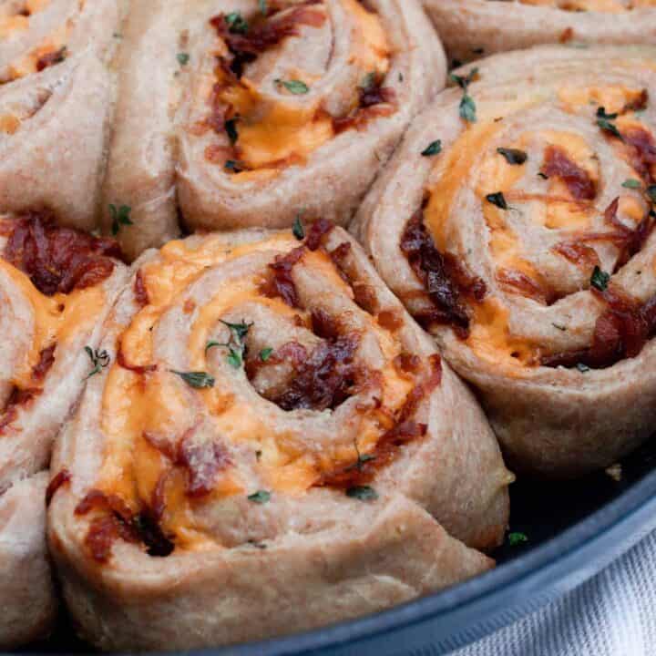 close up picture of sourdough cheese herbs rolls in a cast iron skillet