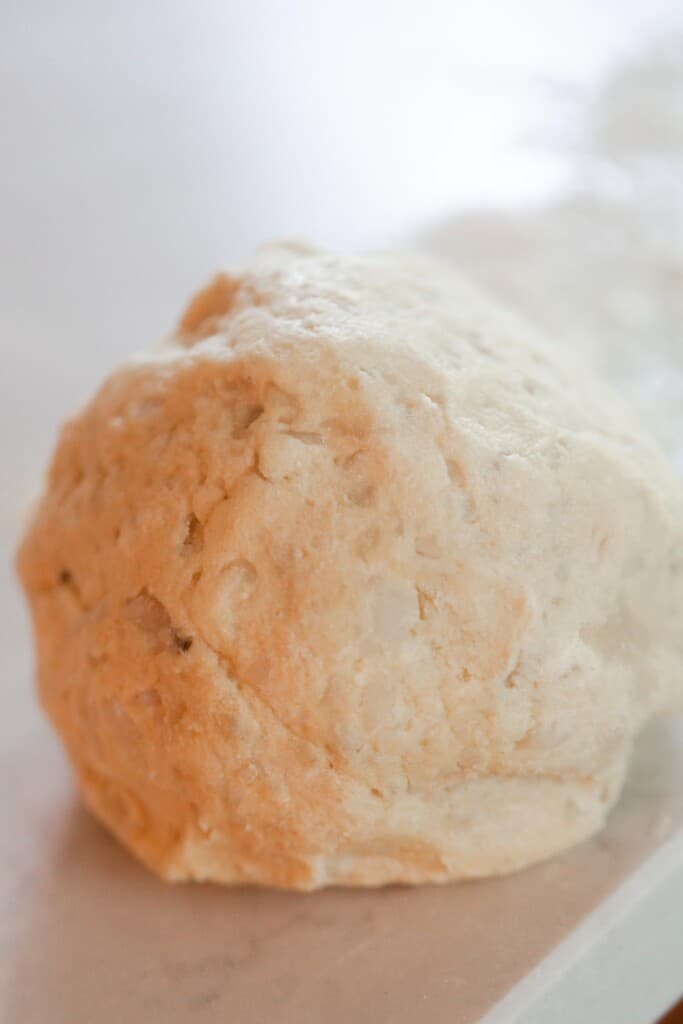 a ball of gnocchi dough on a white quarts countertop