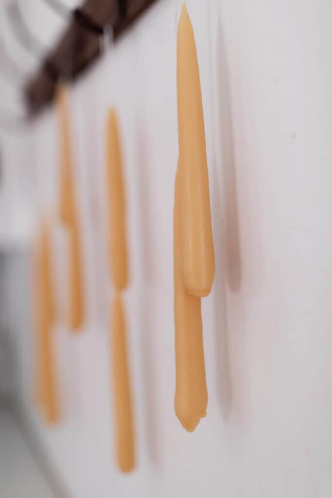 four pairs of dipped beeswax candles handing on a coat hook