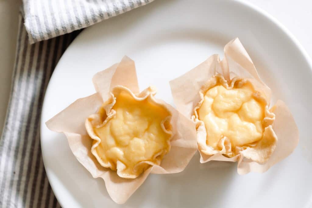 two mini quiche on a white plate resting on a gray and white stripped towel