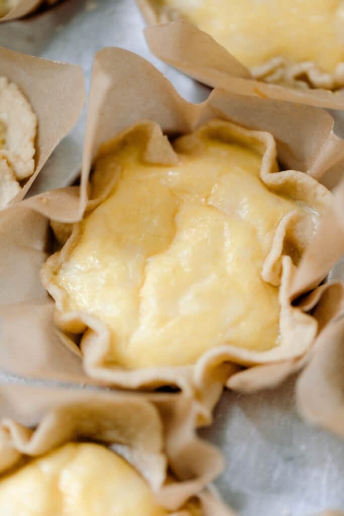 close up of a mini quiche with einkorn crust in a parchment lined muffin tin