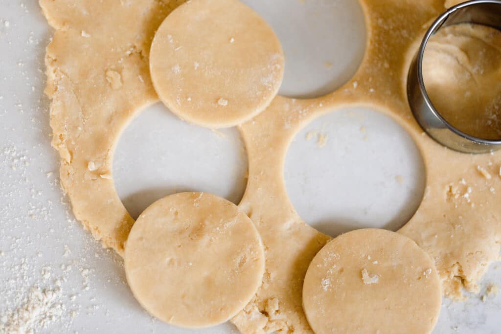 einkorn pie dough rolled out with a biscuit cutter cutting out circles to make mini quiche crust