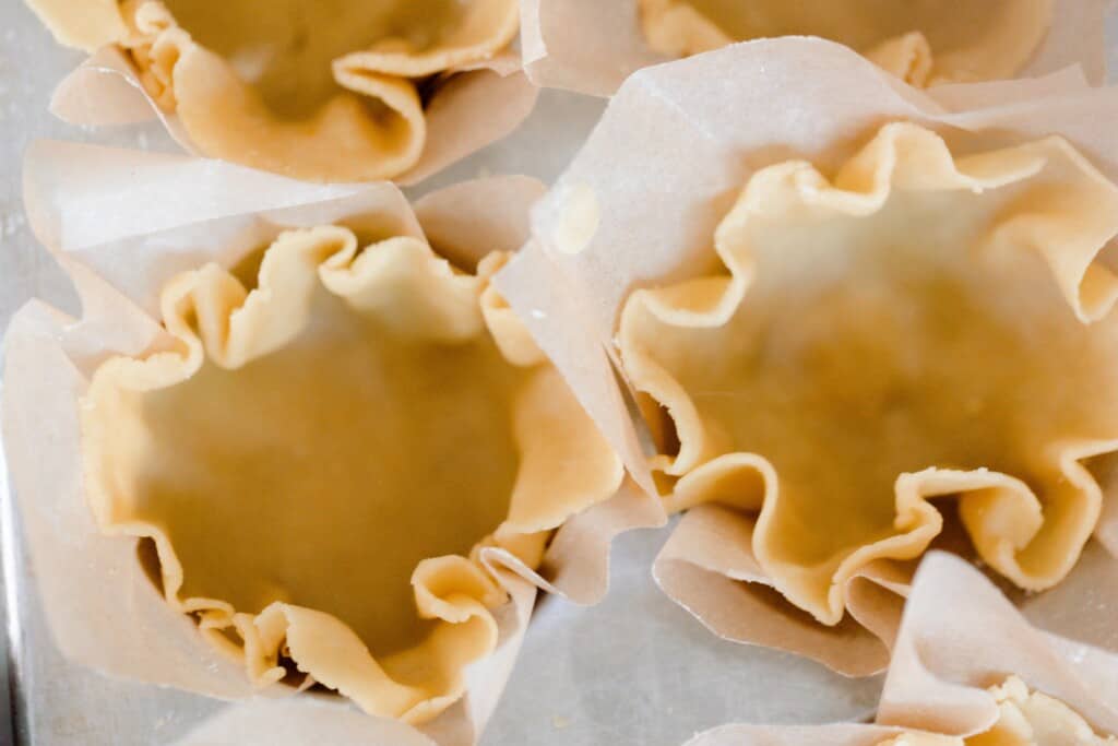 mini einkorn pie crust dough in a parchment lined muffin pan