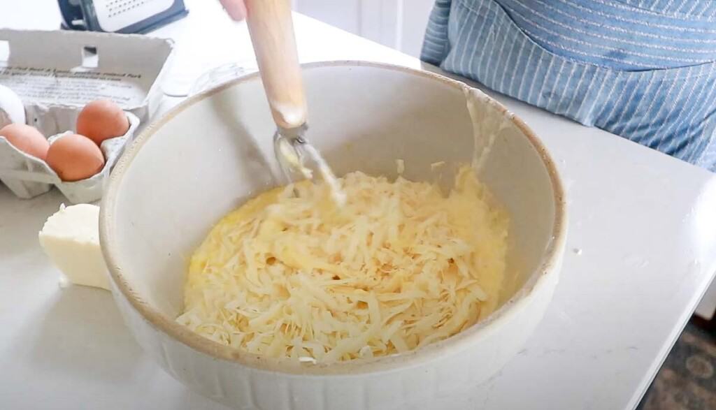 shredded cheese added to sourdough waffle batter with a dough whisk in the batter