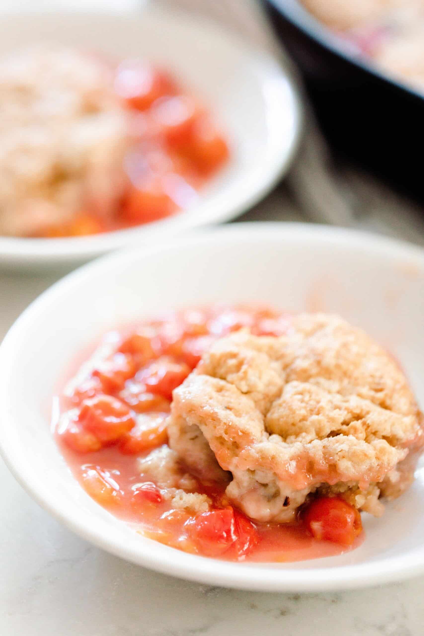 sourdough cherry cobbler in a white bowl with another bowl of cobbler in the background