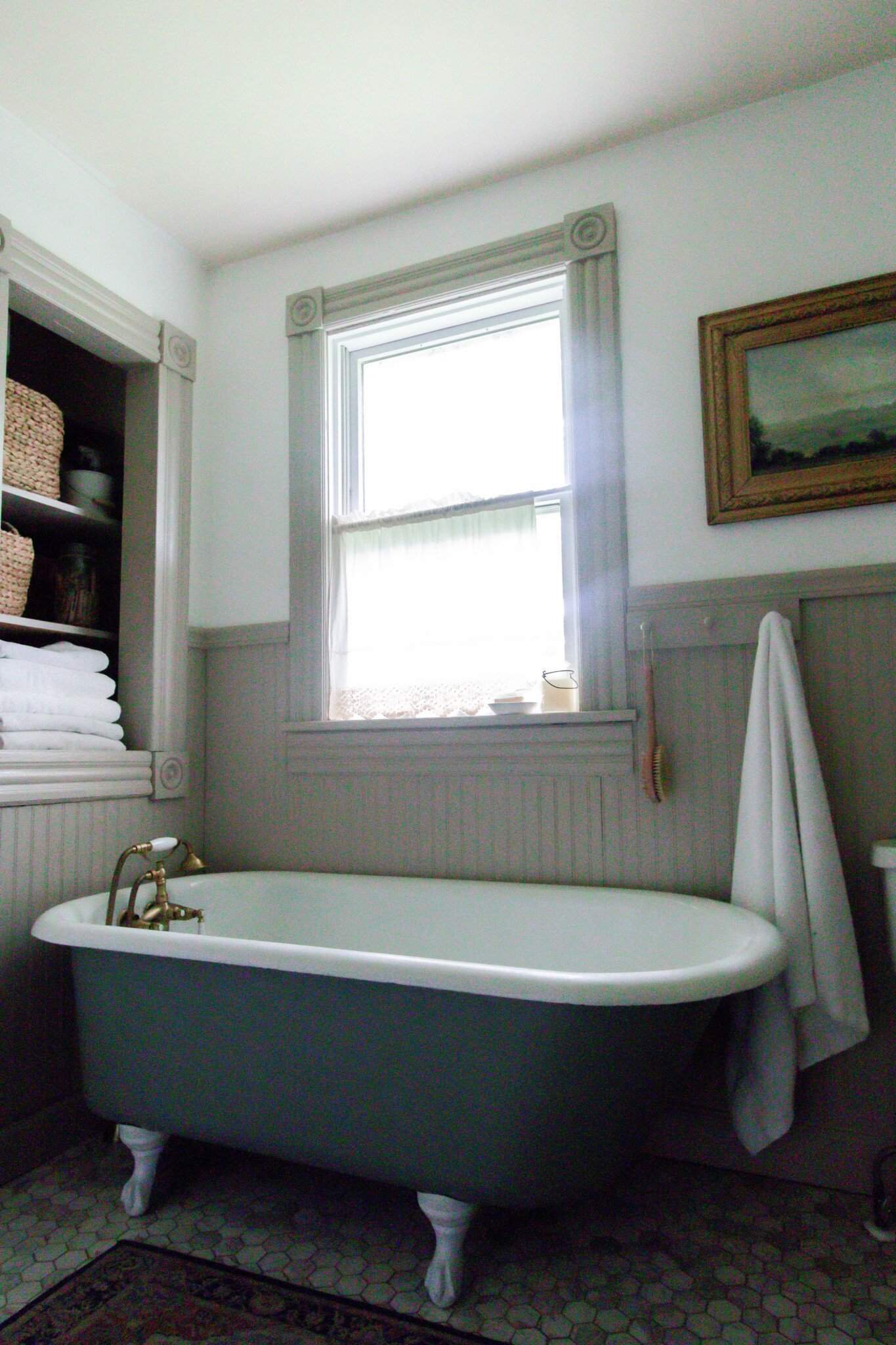 clawfoot tub in a 1800s farmhouse with bead board lined walls and a build in shelves behind the tub