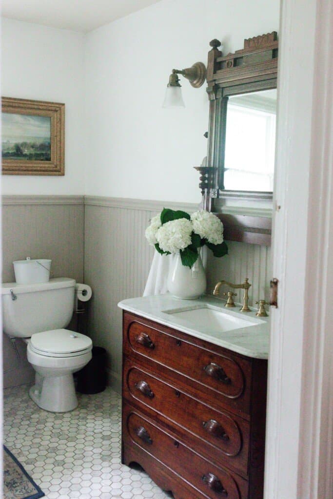 side view into the farmhouse bathroom renovation with antique dresser with marble vanity