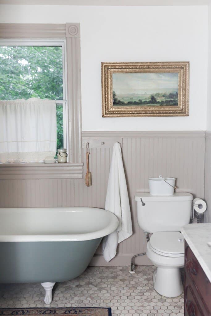 Farmhouse bathroom renovation with printed art in a antique frame over a toilet